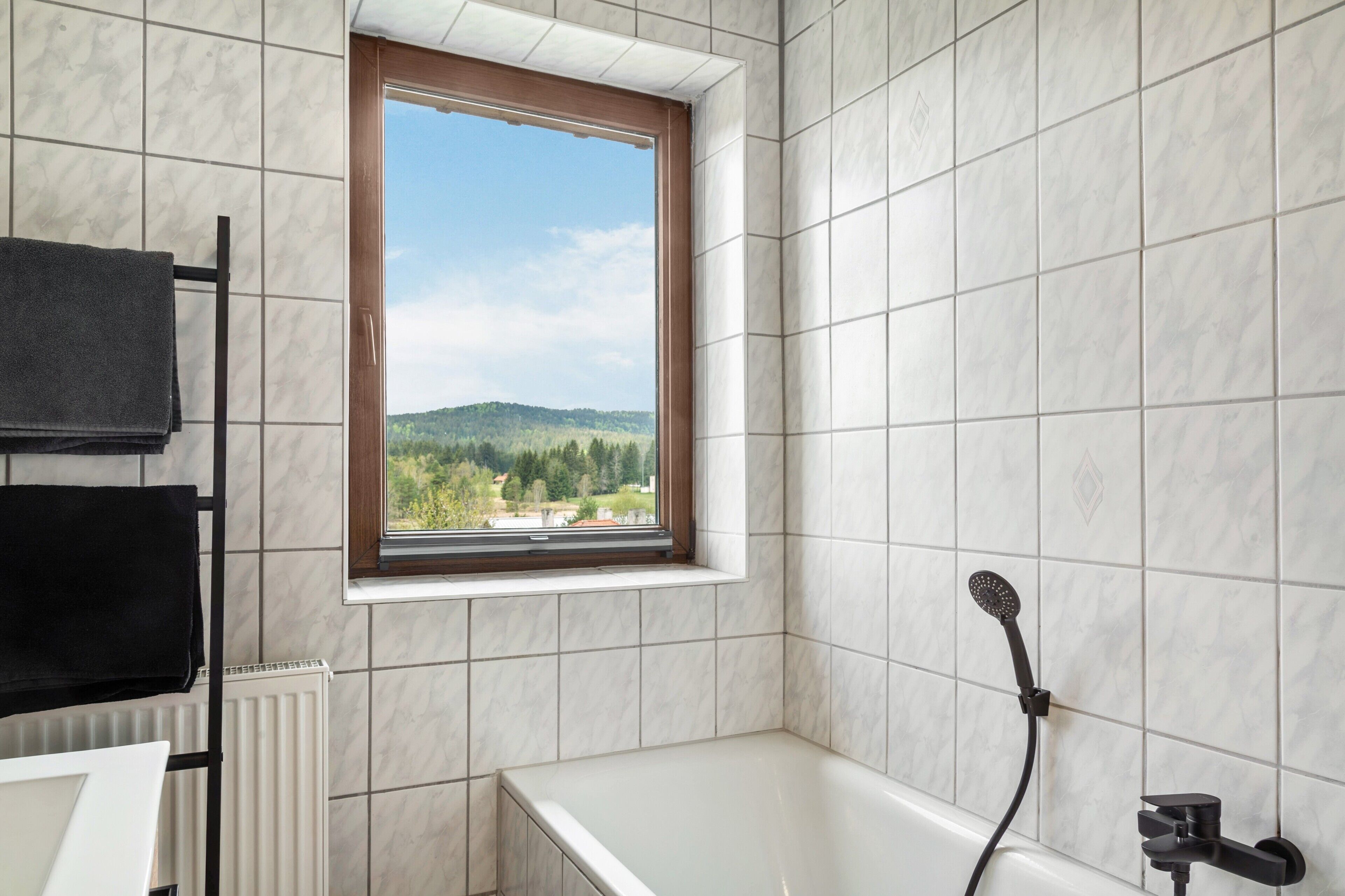 A bathroom with a window, a bathtub, and a towel rack.