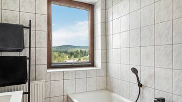 A bathroom with a window, a bathtub, and a towel rack.