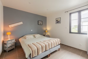 Ein Schlafzimmer mit einem Bett, Nachttischen, einem Wandzeichen und einem Fenster.
