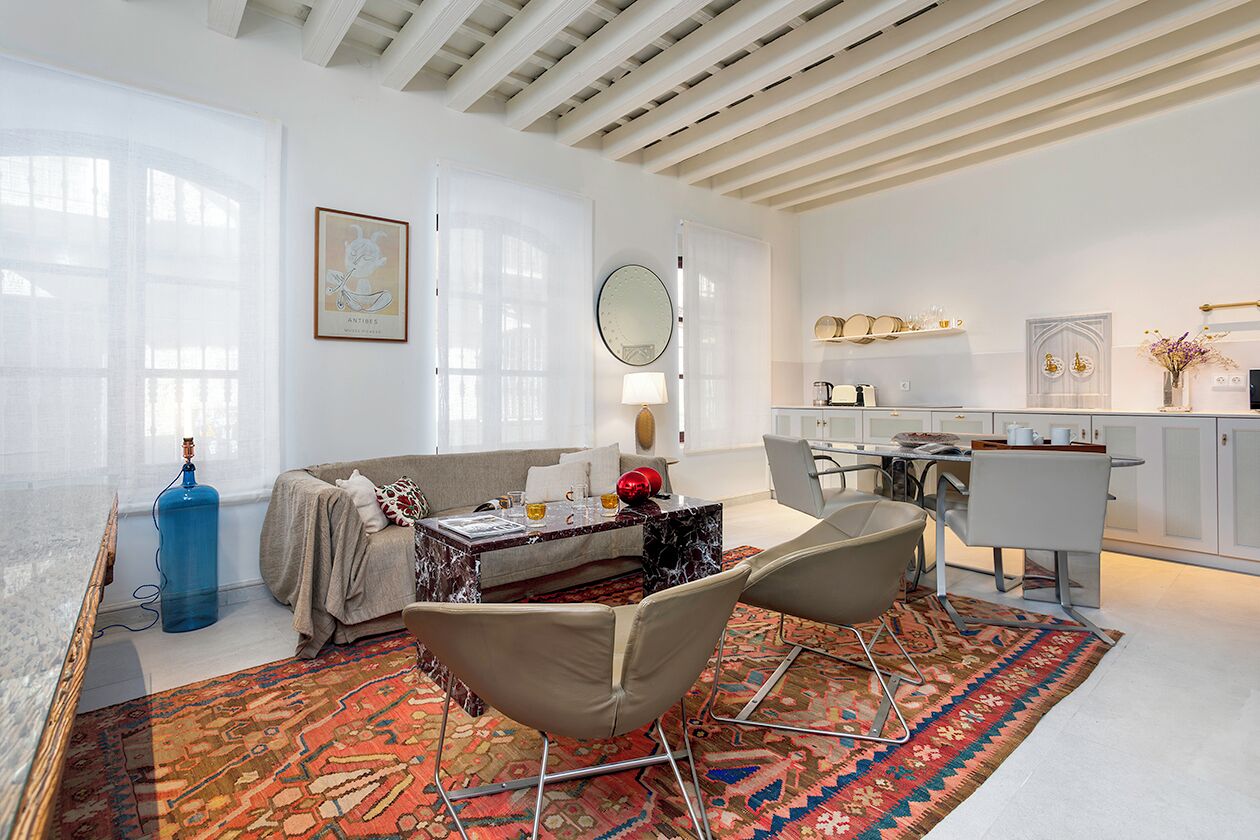 A modern living room with a sofa, a coffee table, and a dining area with chairs.
