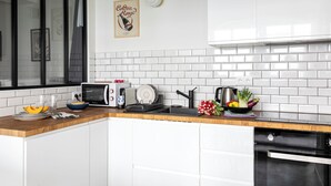 A modern kitchen with white cabinets, a microwave, a toaster, and a sink. - Bright & renovated: Haven of peace for 4 in Paris (Paris)
