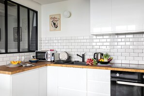 A modern kitchen with white cabinets, a microwave, a toaster, and a sink. - Bright & renovated: Haven of peace for 4 in Paris (Paris)