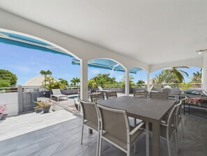 Une terrasse extérieure avec une table à manger, des chaises et un barbecue.