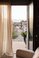 En balkon med udsigt over en gade, en rød bil og bygninger i det fjerne.