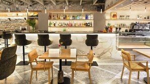 Un espace bar doté d’un comptoir en marbre, de plusieurs tabourets et d’une variété de bouteilles.