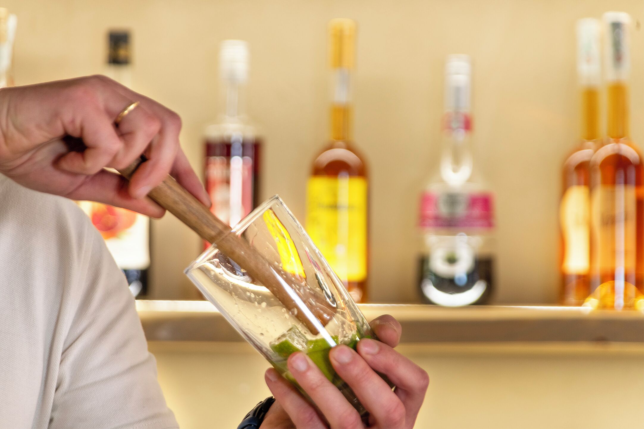 A person mixing a drink with a shaker in a bar setting.