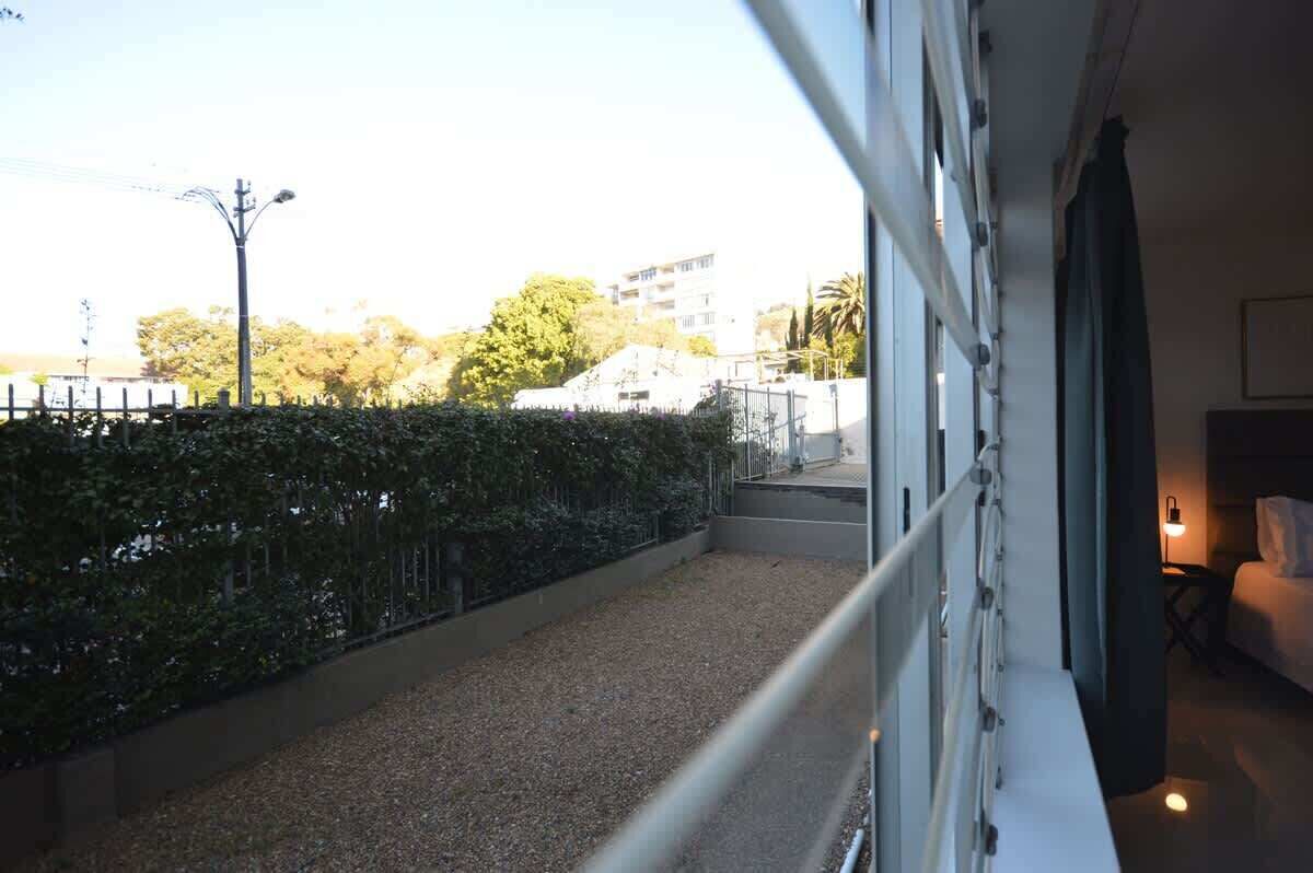 A balcony with a gravel path, a metal railing, and a view of buildings and trees.