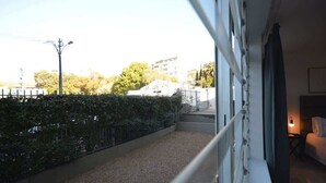 Ein Balkon mit Kiesweg, Metallgeländer und Blick auf Gebäude und Bäume.