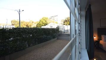 A balcony with a gravel path, a metal railing, and a view of buildings and trees.