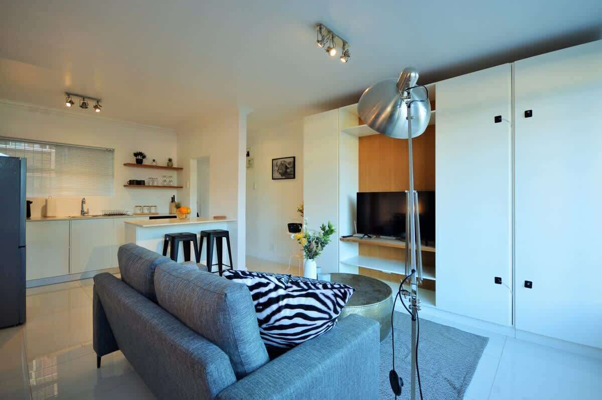 A modern living room with a sofa, a TV, and a lamp.