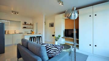 A modern living room with a sofa, a TV, and a lamp.