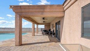 A covered outdoor area with a pool, seating, and a ceiling fan. - Sabino Gorgeous Heatable Pool Retreat (Lake Havasu City)