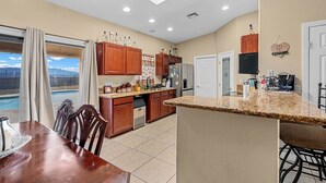 A kitchen with a dining area, a pool view, and a ceiling fan. - Sabino Gorgeous Heatable Pool Retreat (Lake Havasu City)