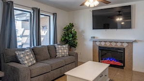 A living room with a sofa, a white side table, a fireplace, and a ceiling fan. - Constellation of Havasu - Views, Pool, Spa (Lake Havasu City)