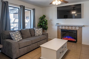 A living room with a sofa, a white side table, a fireplace, and a ceiling fan. - Constellation of Havasu - Views, Pool, Spa (Lake Havasu City)