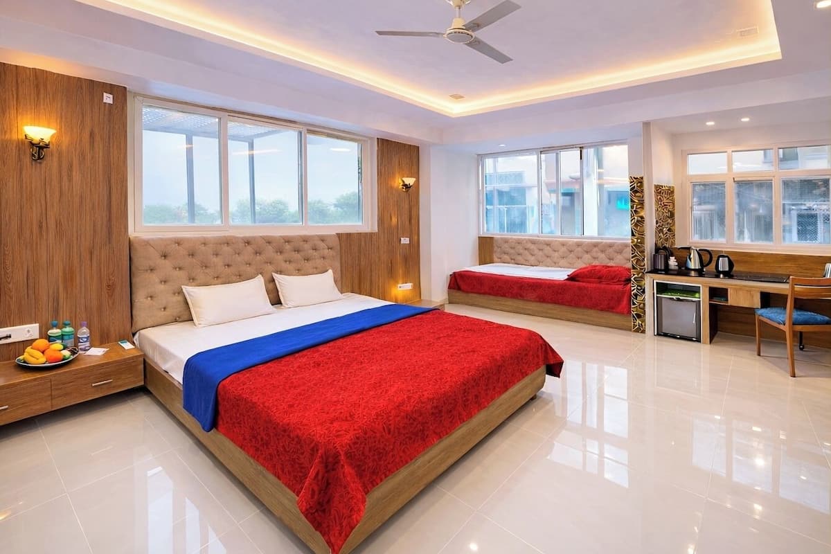 A modern hotel room with two beds, a desk, and a view of the city.