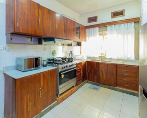 A kitchen with wooden cabinets, a microwave, a stove, and a sink.