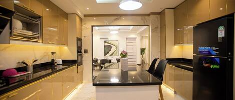 A modern kitchen with a central island, built-in appliances, and a dining area with a view into the living room.