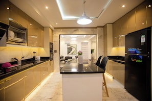 Una cocina moderna con una isla central, electrodomésticos integrados y un comedor con vista al salón.