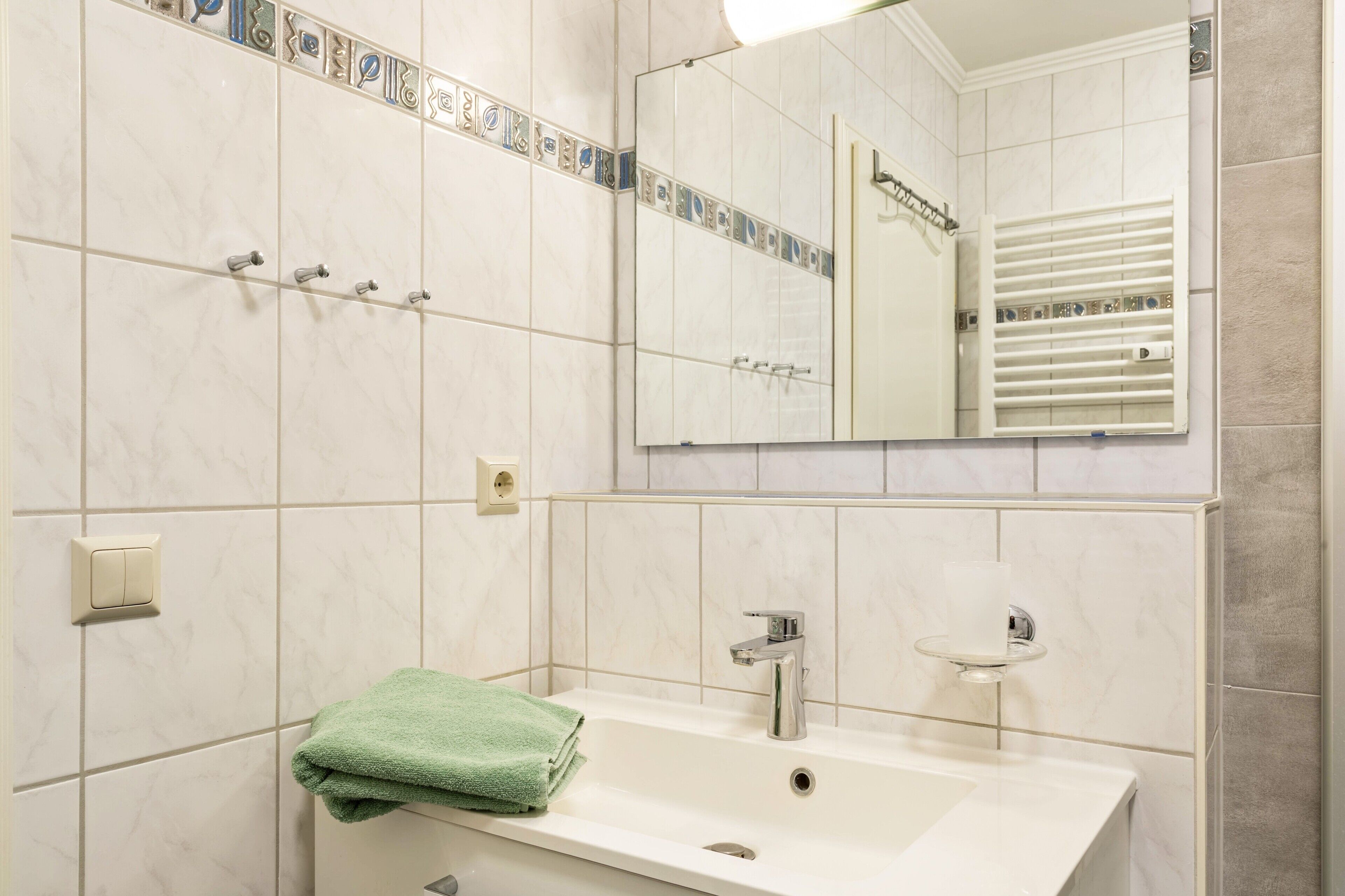 A bathroom with a white sink, a mirror, and a towel rack.