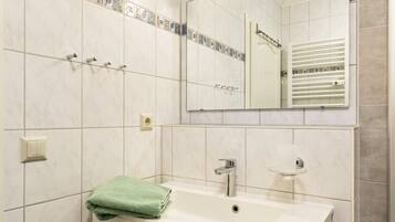 A bathroom with a white sink, a mirror, and a towel rack.