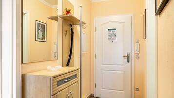 A bathroom with a mirror, a sink, a towel, a door with a sign, and a shelf with a teddy bear.