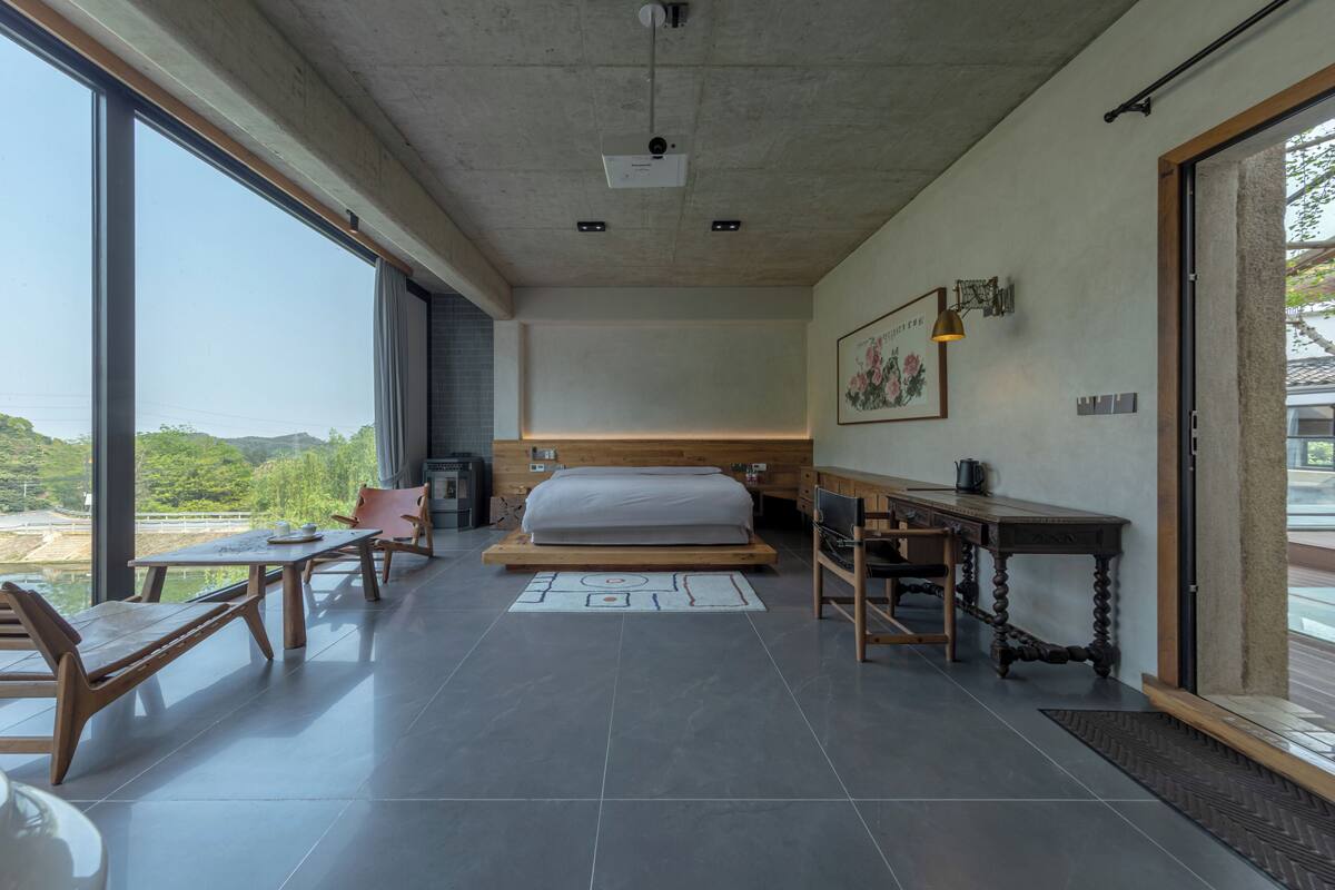 A modern room with a bed, a desk, a chair, and a dining table.
