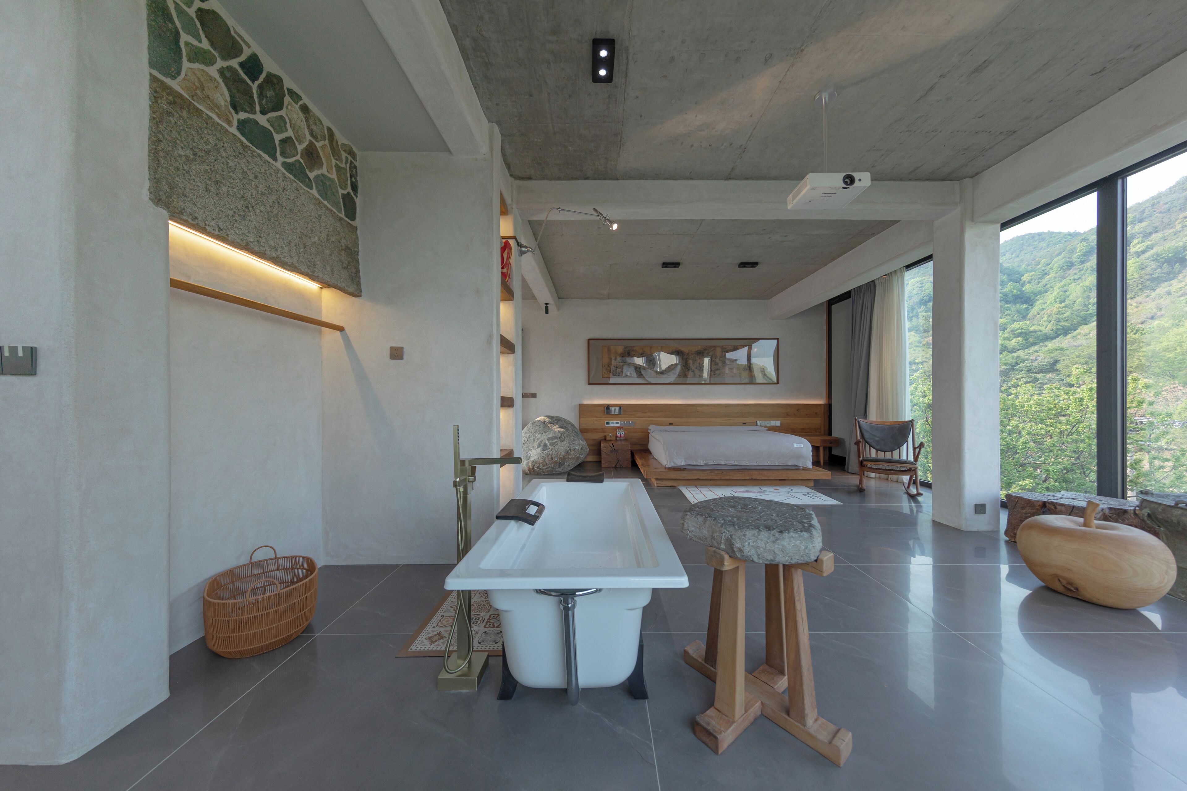 Un baño moderno con una bañera grande, un taburete de madera y un lavabo de piedra.