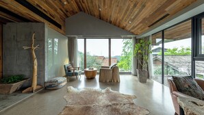 A spacious living room with a high ceiling, large windows, and a view of the outdoors.