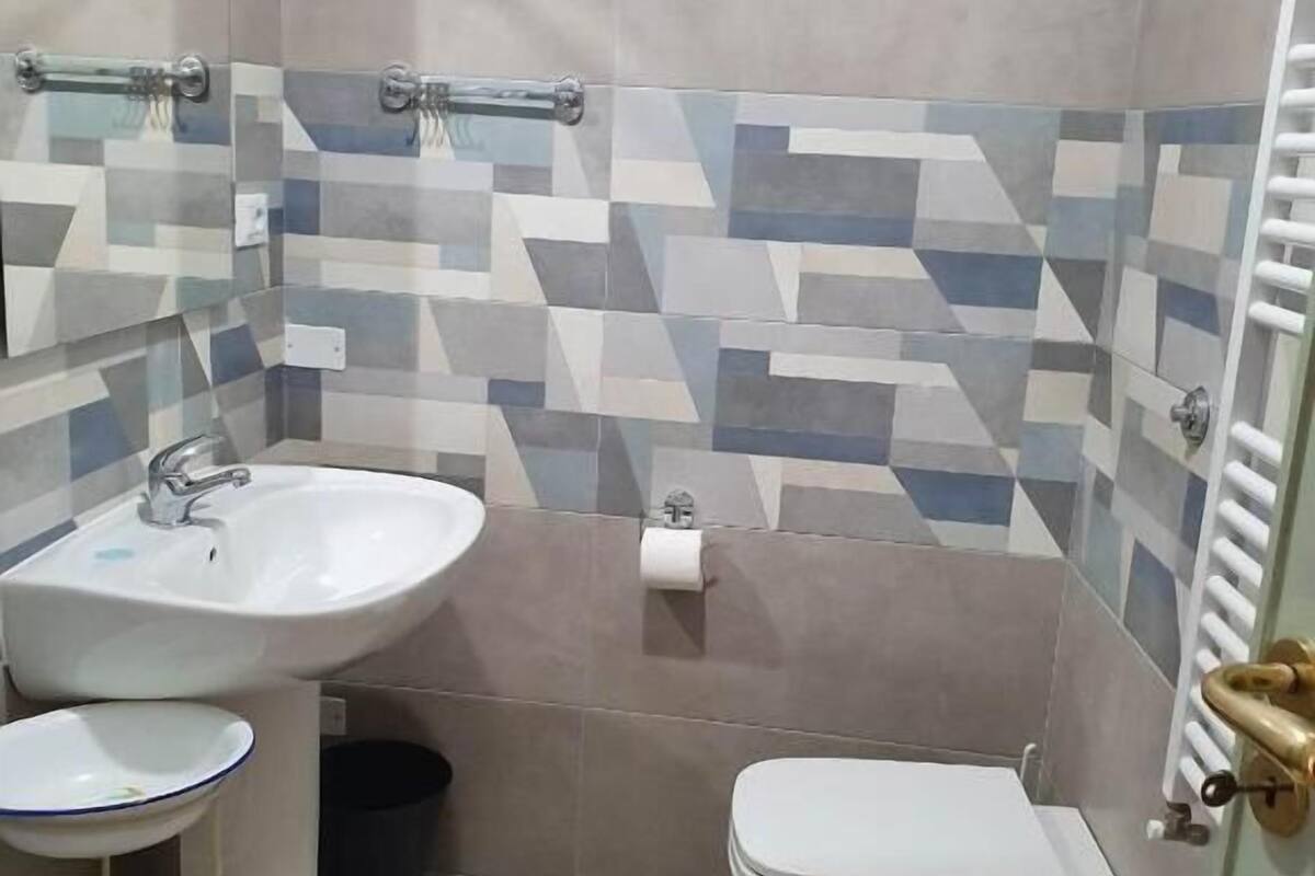 A bathroom with a sink, toilet, bidet, and a mirror.