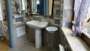 Un baño con lavamanos pedestal, espejo y ventana con cortina.