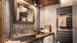 A bathroom with a stone sink, a mirror, a towel rack, and a washing machine. - Your summer retreat in the heart of the mountains, services included (Aime-la-Plagne)