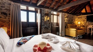A room with a bed, a chair, a stone wall, and a wooden ceiling. - Hotel Emblemático Duque de la Torre (Arona)