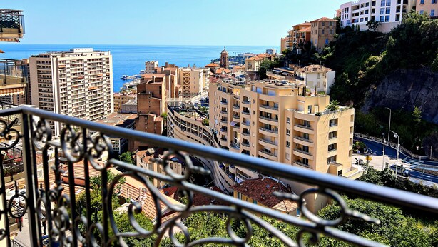 A coastal cityscape with high-rise buildings, a clear blue sky, and a view of the sea. - Appartement 8A - MyResidenced'Azur (Beausoleil)