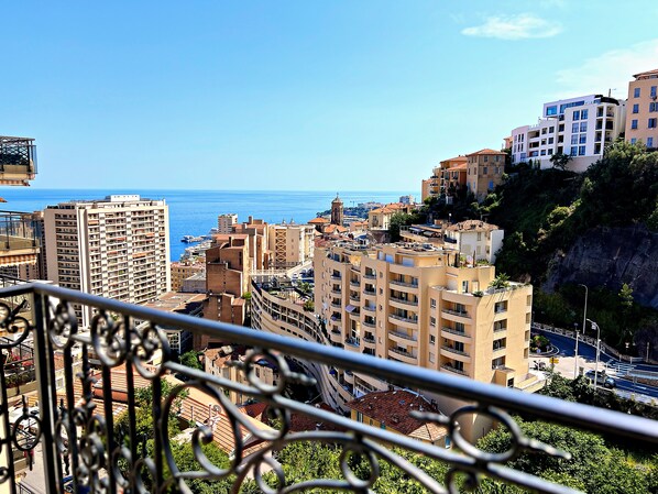 A coastal cityscape with high-rise buildings, a clear blue sky, and a view of the sea. - Appartement 8A - MyResidenced'Azur (Beausoleil)