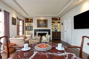 A living room with a fireplace, a dining table with a marble top, and a bookshelf filled with books. - Stunning Palace With Terrace in C diz Center Calderon de la Barca (Cádiz)