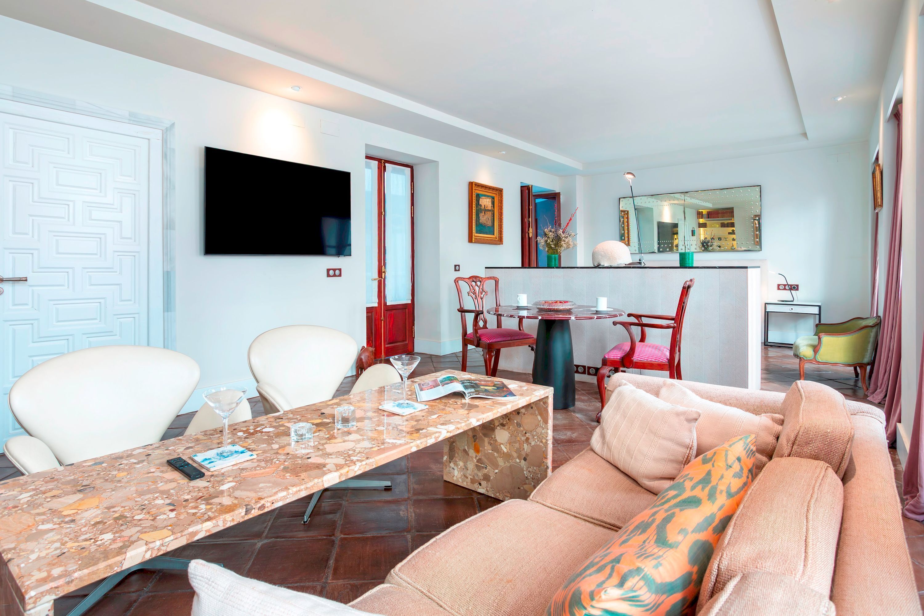 Una sala de estar con un sofá, sillas, una mesa de centro, un televisor y un comedor con sillas y una mesa.