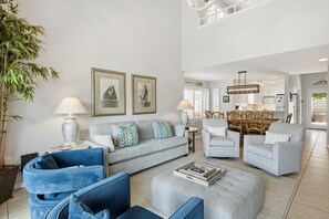 Ein geräumiges Wohnzimmer mit grauem Sofa, blauen Sesseln und einem Essbereich mit Holzmöbeln.