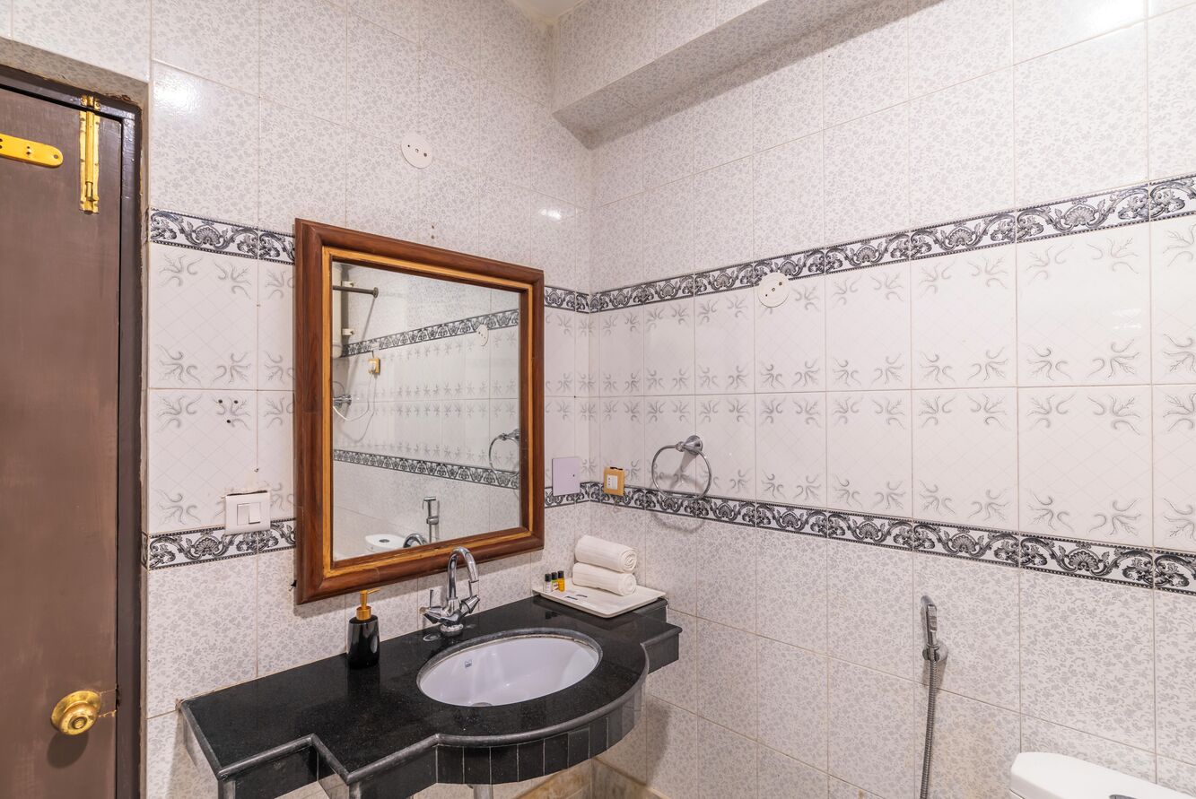 A bathroom with a sink, mirror, towel rack, and shower.