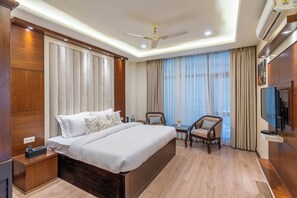 Habitación de hotel con una cama grande, dos sillones, una mesita, televisor y aire acondicionado.