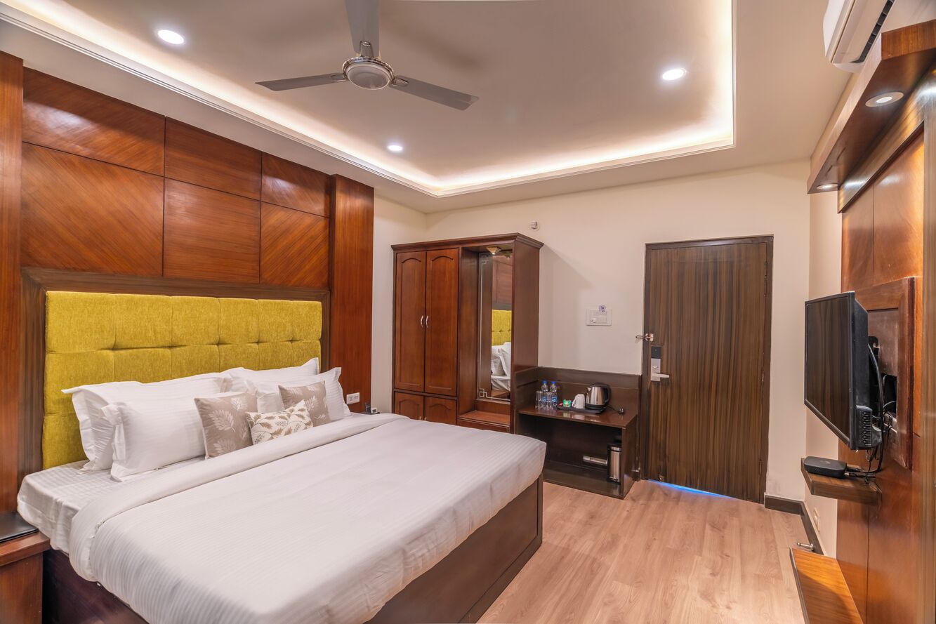 A hotel room with a bed, wardrobe, mirror, TV, and ceiling fan.