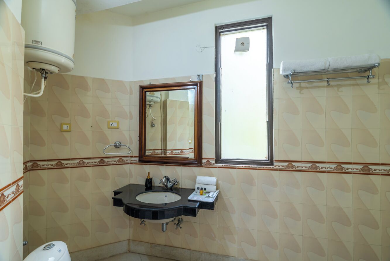 A bathroom with a sink, mirror, towel rack, and a window.