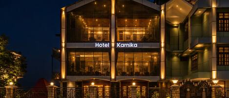 A hotel with a modern facade, large glass windows, and a sign indicating it's named 'Hotel Karnika.'