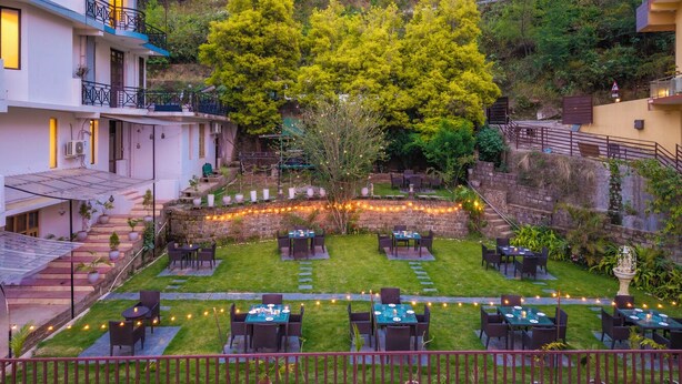 A courtyard with outdoor seating, a stone wall, and a staircase leading to a building.