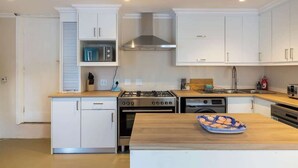 Una cocina moderna con armarios blancos, electrodomésticos de acero inoxidable y encimera de madera.