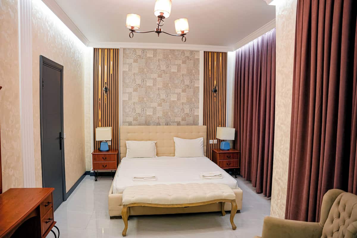 Una habitación de hotel con una cama grande, mesitas de noche, un escritorio y una silla.