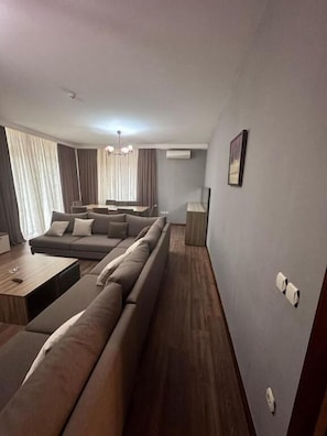 Een moderne woonkamer met een modulaire bank, een eettafel en een kroonluchter.