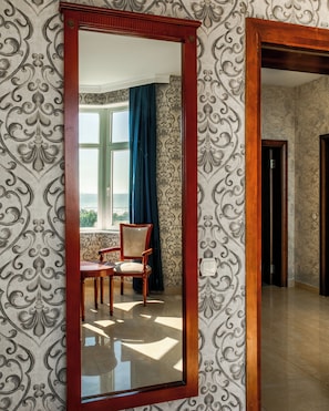 A room with a large mirror, patterned wallpaper, a chair, and a view of the outdoors through a window. - Khazri Resort & Villas (Baku)