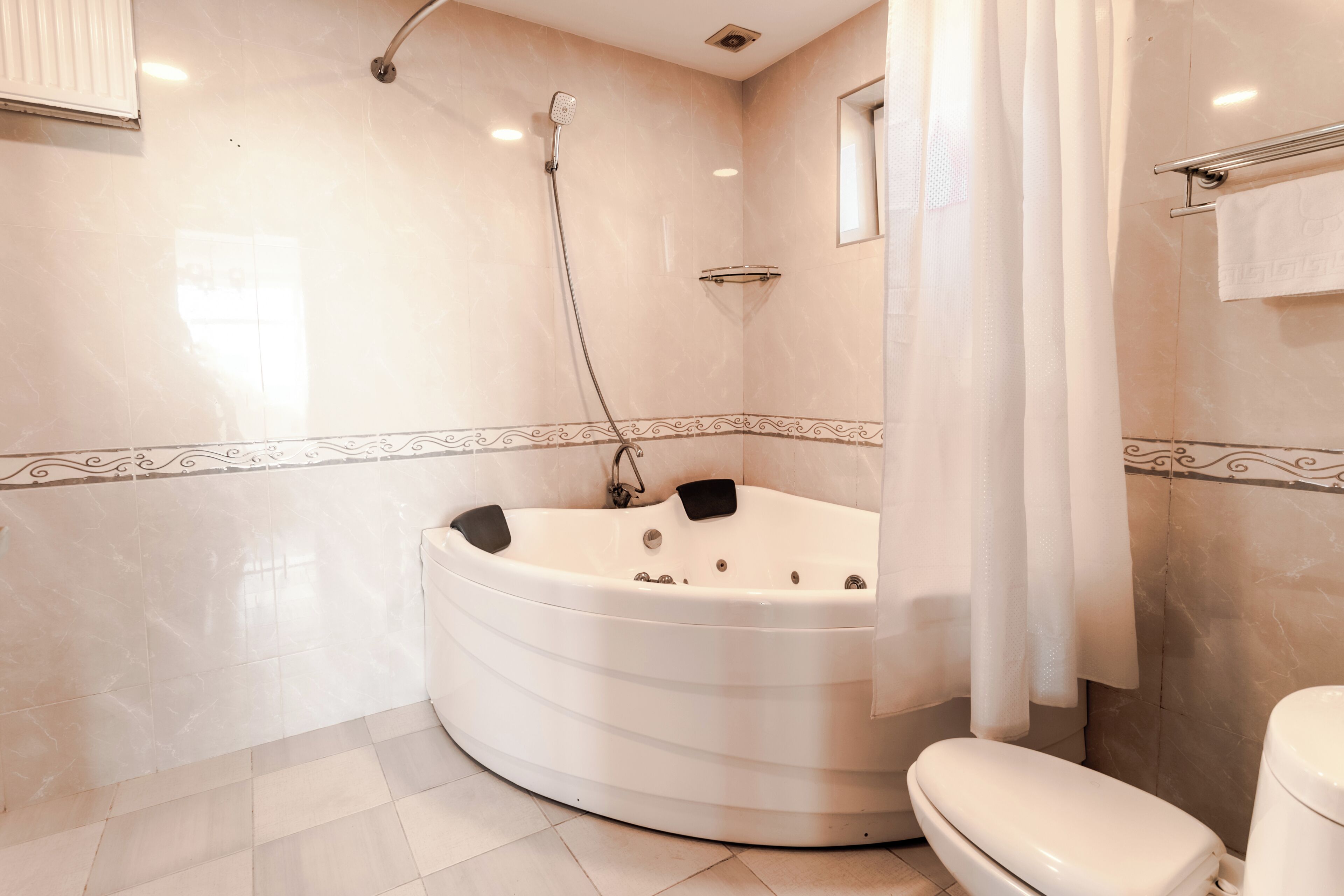 A bathroom with a freestanding bathtub, a toilet, a showerhead, and a towel rack.
