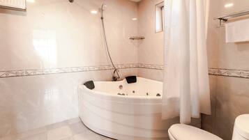 A bathroom with a freestanding bathtub, a toilet, a showerhead, and a towel rack.